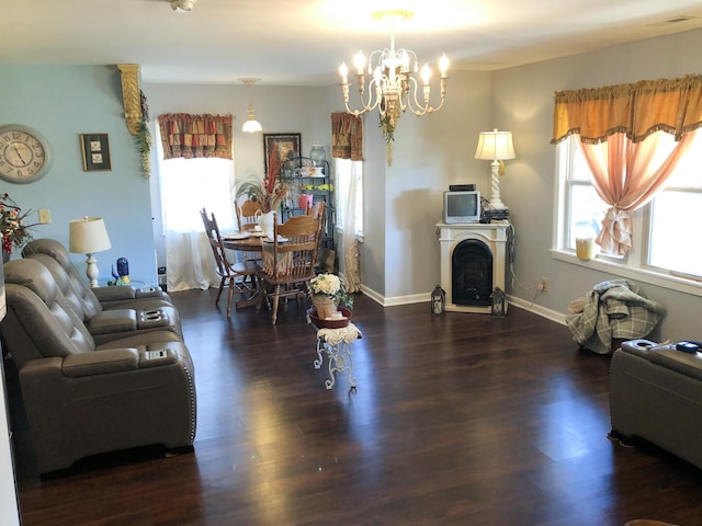 living room featuring baseboards, a healthy amount of sunlight, wood finished floors, and a chandelier