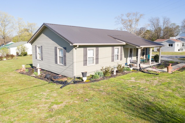 rear view of house with metal roof and a yard