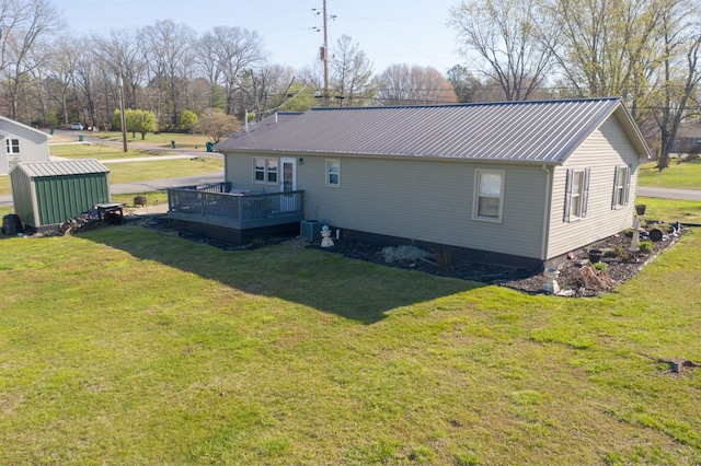 view of home's exterior featuring metal roof, an outbuilding, a deck, and a yard