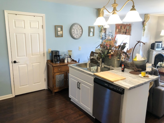 kitchen featuring light countertops, white cabinets, dark wood-type flooring, a sink, and stainless steel dishwasher