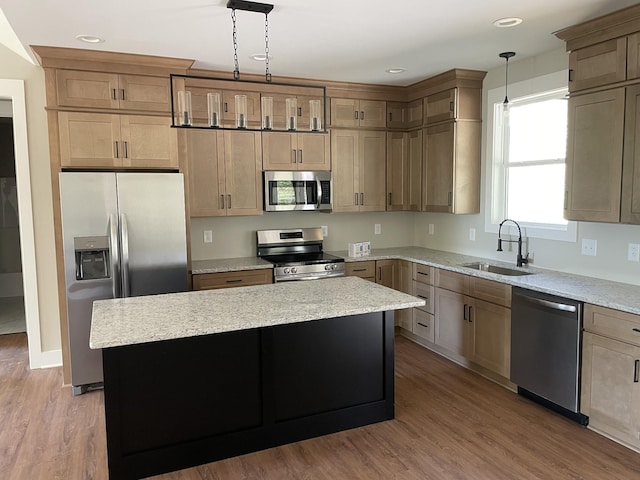 kitchen featuring stainless steel appliances, wood finished floors, a sink, and a kitchen island