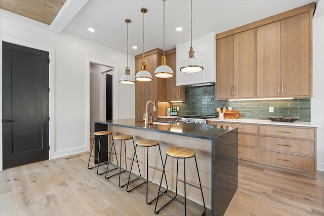 2510 Vaulx Ln, Nashville, TN 37204 - kitchen featuring tasteful backsplash, a sink, light wood-type flooring, a breakfast bar, and an island with sink