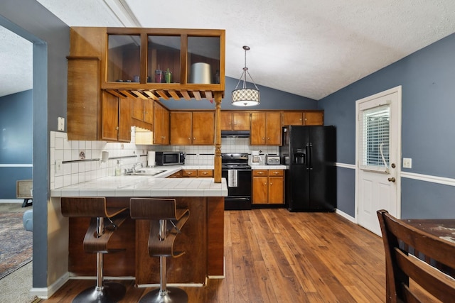 4825 Peppertree Dr, Antioch, TN 37013 - kitchen with lofted ceiling, brown cabinets, a peninsula, black appliances, and ventilation hood