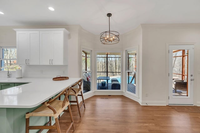 1237 Temple Ridge Dr, Nashville, TN 37221 - kitchen with light countertops, white cabinets, light wood-style floors, an inviting chandelier, and a kitchen breakfast bar