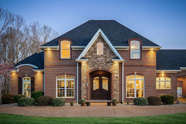 view of front of house featuring brick siding, a shingled roof, and french doors