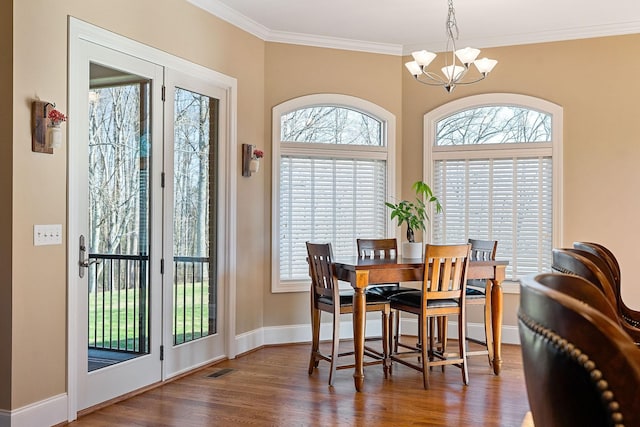 dining area with ornamental molding, a notable chandelier, baseboards, and wood finished floors