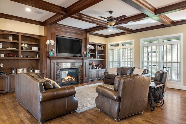 living area featuring coffered ceiling, a high end fireplace, wood finished floors, and a ceiling fan