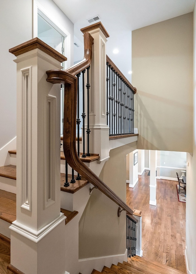 stairway featuring baseboards, visible vents, and wood finished floors