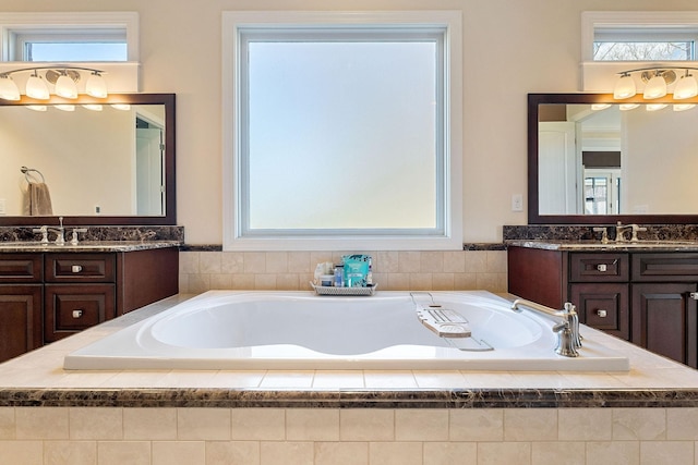 full bathroom with a bath, a sink, and two vanities