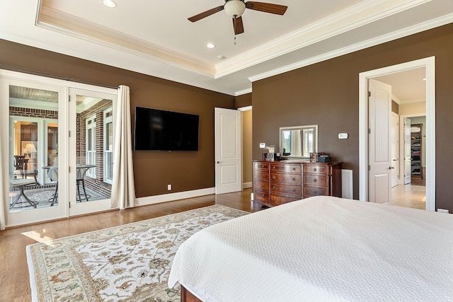 bedroom featuring baseboards, ornamental molding, access to outside, wood finished floors, and a tray ceiling