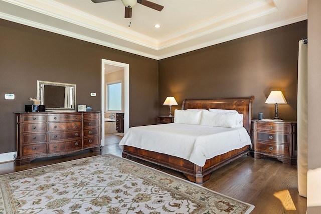 bedroom featuring a tray ceiling, crown molding, wood finished floors, and ensuite bathroom