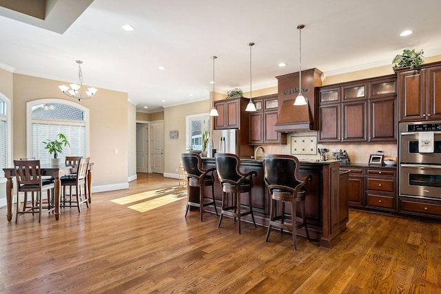 kitchen with a kitchen bar, dark wood finished floors, stainless steel appliances, decorative backsplash, and an inviting chandelier