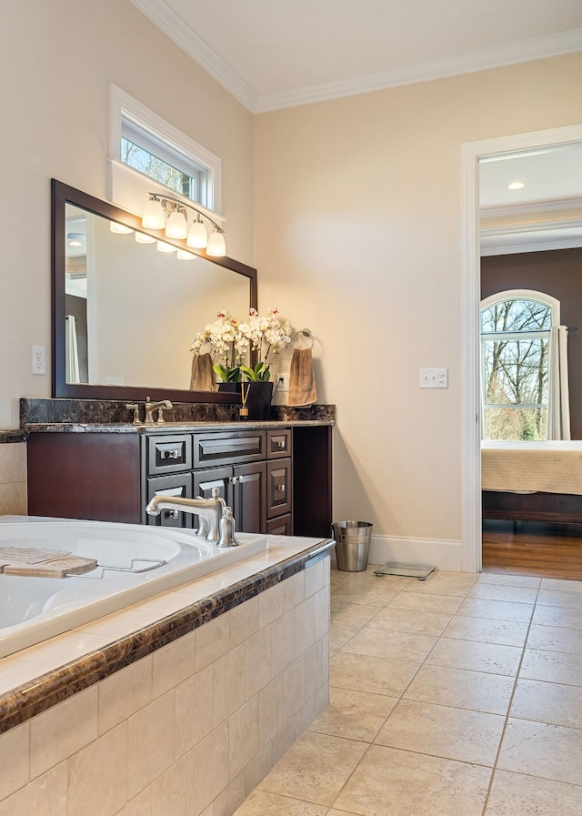 ensuite bathroom featuring vanity, ornamental molding, baseboards, tiled tub, and ensuite bath
