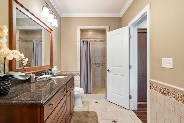 full bathroom featuring ornamental molding, a tile shower, toilet, and wainscoting