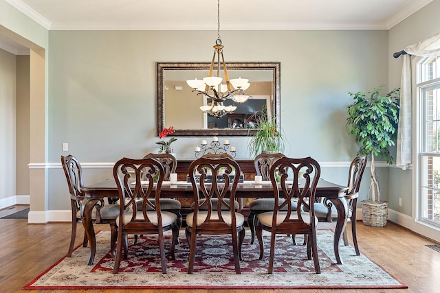 dining space with an inviting chandelier, ornamental molding, baseboards, and wood finished floors