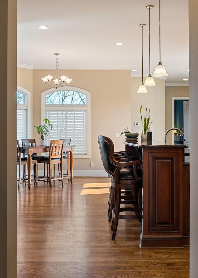 dining room with an inviting chandelier, dark wood-style flooring, ornamental molding, and baseboards