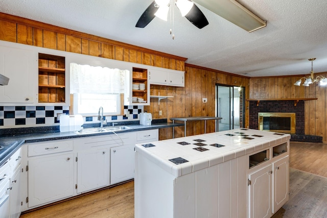 kitchen with white cabinetry, a sink, open shelves, light wood-type flooring, and a center island