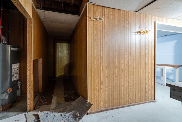 corridor featuring water heater and wood walls