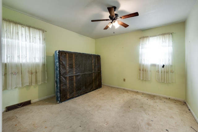 unfurnished bedroom with baseboards, a ceiling fan, visible vents, and carpet