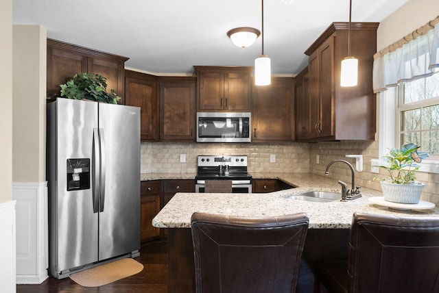 kitchen featuring stainless steel appliances, dark wood-type flooring, a sink, a peninsula, and dark brown cabinets