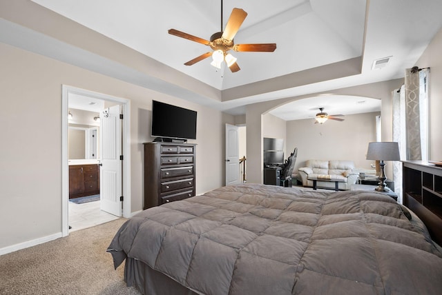 bedroom featuring a raised ceiling, arched walkways, light colored carpet, and visible vents