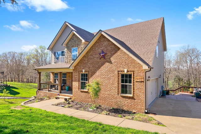 view of front facade with covered porch, a garage, brick siding, and a front yard