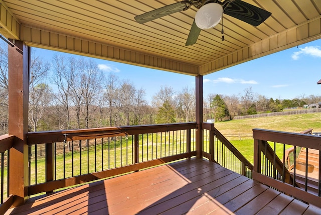 deck with ceiling fan, fence, and a yard
