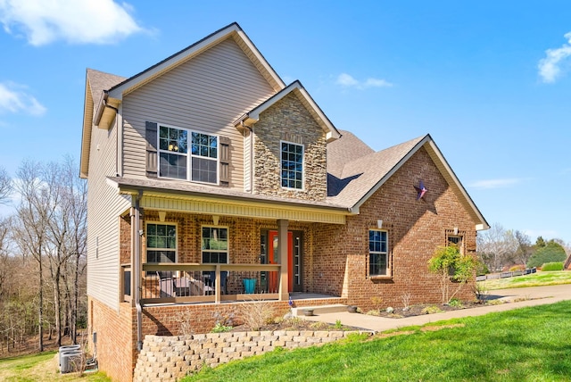 traditional home with brick siding, a porch, central AC, and a front lawn