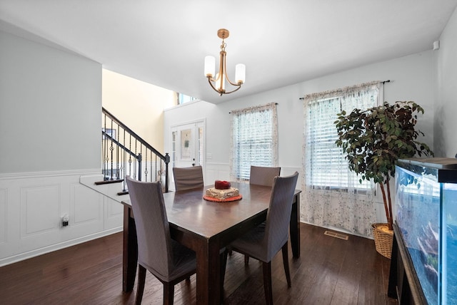 dining room featuring a wainscoted wall, visible vents, stairs, dark wood finished floors, and a notable chandelier
