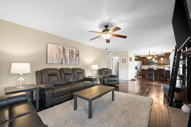 living room featuring wainscoting, ceiling fan, and dark wood-type flooring
