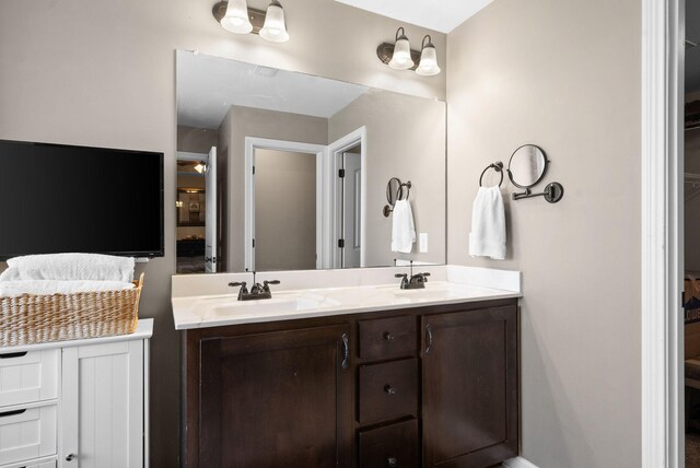 full bath featuring double vanity, a spacious closet, and a sink