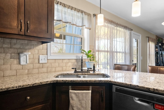 kitchen with dishwashing machine, tasteful backsplash, light stone countertops, and a sink