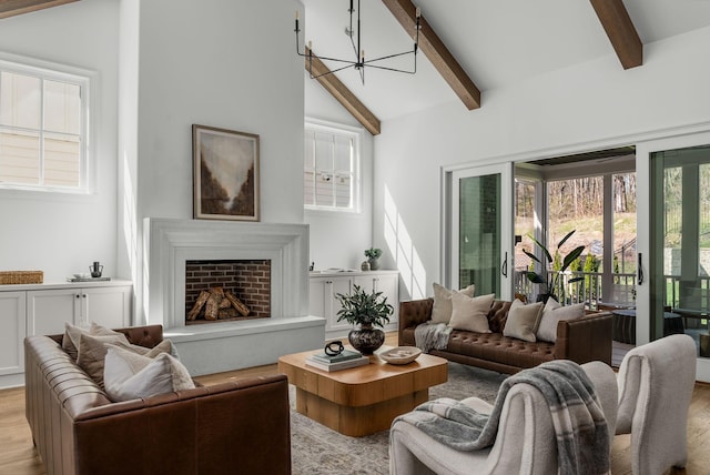 living area with a fireplace with raised hearth, a chandelier, light wood-style floors, and beamed ceiling