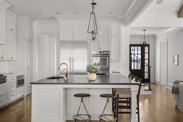 kitchen with white cabinetry, ornamental molding, built in appliances, and dark countertops