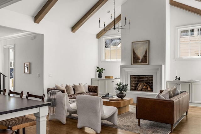 living room with a fireplace with raised hearth, vaulted ceiling with beams, and wood finished floors