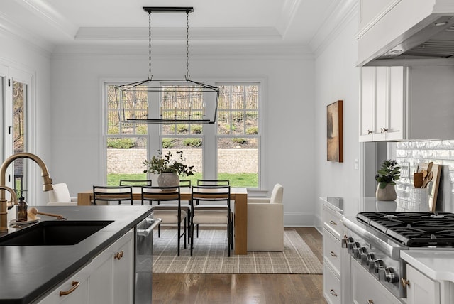 kitchen featuring stainless steel gas stovetop, dark wood-type flooring, a sink, wall chimney range hood, and an inviting chandelier