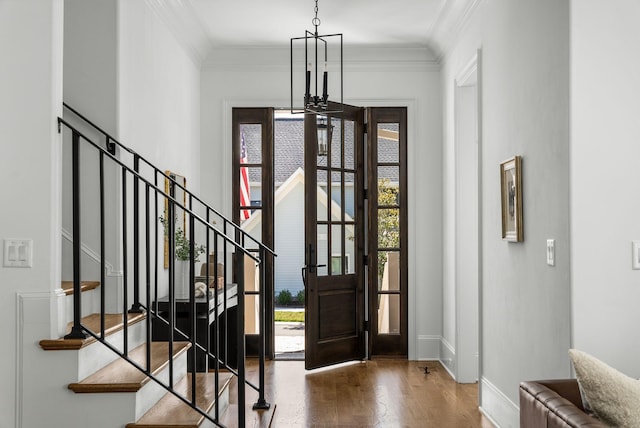 entryway featuring a chandelier, crown molding, baseboards, wood finished floors, and stairway