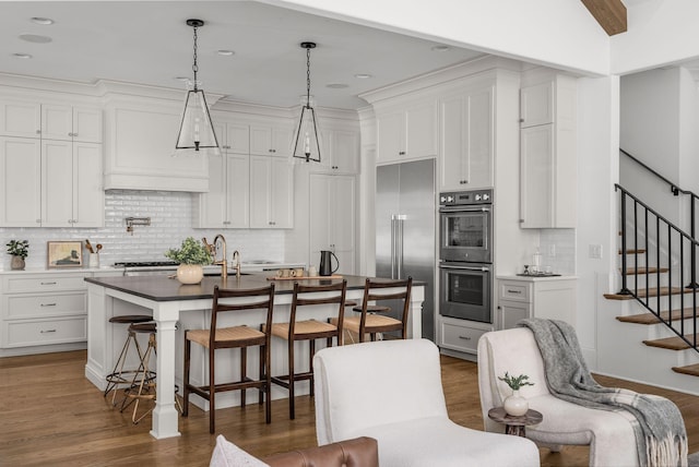 kitchen featuring white cabinets, stainless steel appliances, a breakfast bar, and wood finished floors