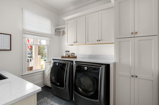 clothes washing area with cabinet space, washing machine and dryer, and ornamental molding