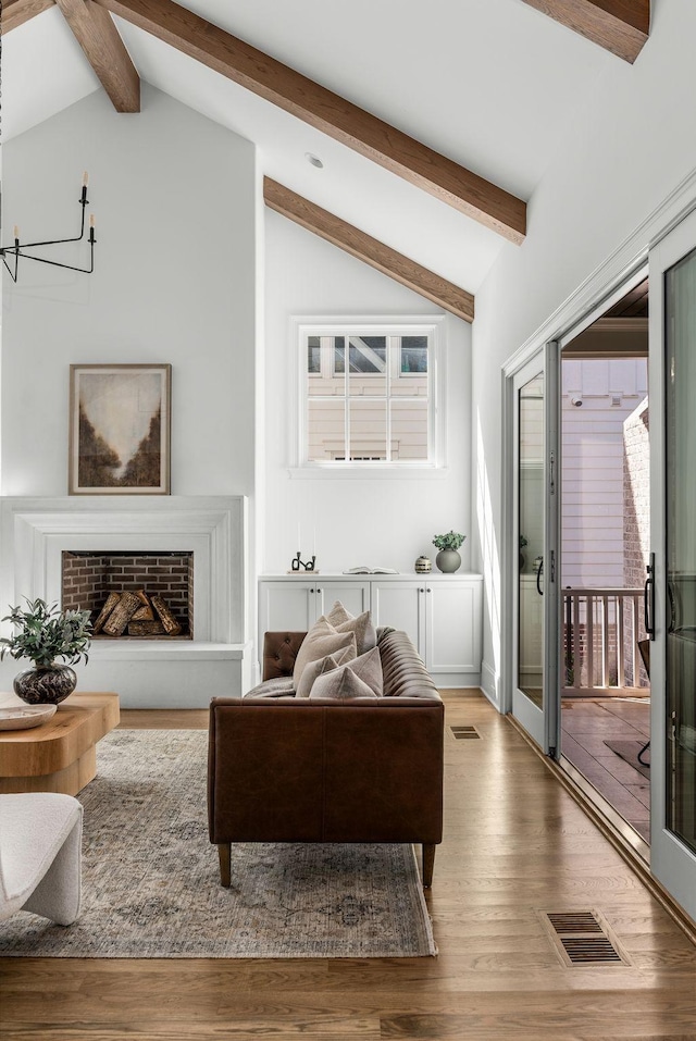 living room with lofted ceiling with beams, visible vents, and wood finished floors