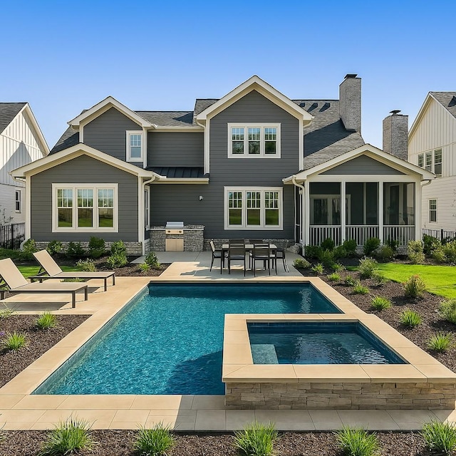 back of property featuring an outdoor pool, a sunroom, fence, a patio, and an outdoor kitchen