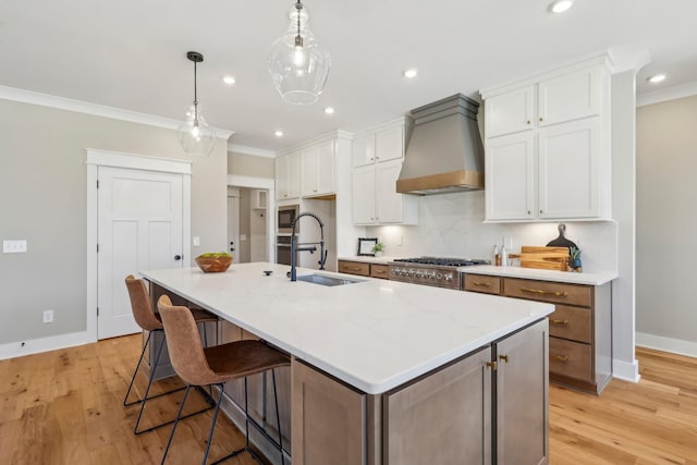 6477 Simmons Acres Ln, Lascassas, TN 37085 - kitchen featuring custom range hood, ornamental molding, white cabinets, a center island with sink, and light wood finished floors