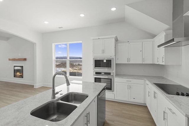166 Oasis Dr, La Vergne, TN 37086 - kitchen with a sink, wall chimney range hood, a warm lit fireplace, light stone countertops, and appliances with stainless steel finishes