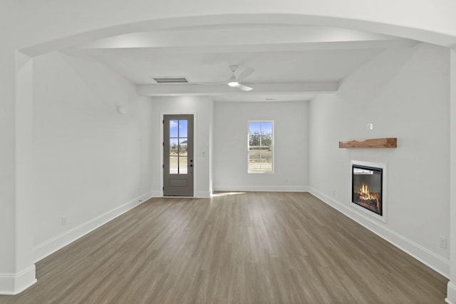 166 Oasis Dr, La Vergne, TN 37086 - unfurnished living room featuring baseboards, wood finished floors, a glass covered fireplace, and a ceiling fan