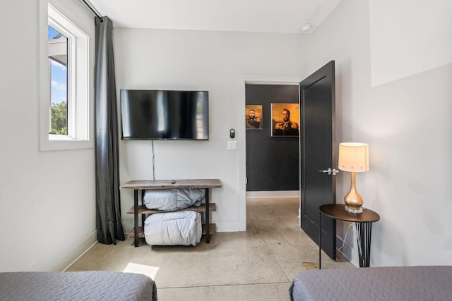 bedroom with concrete flooring and baseboards
