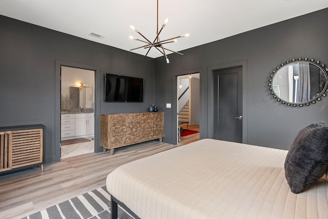 bedroom featuring light wood-style flooring, a notable chandelier, connected bathroom, and visible vents