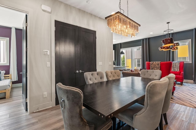 dining space featuring an inviting chandelier, baseboards, and light wood-style floors