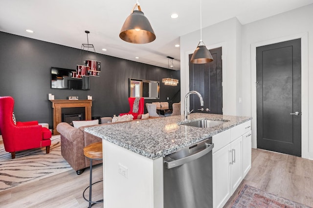 kitchen featuring light wood-style flooring, a sink, stainless steel dishwasher, and white cabinets