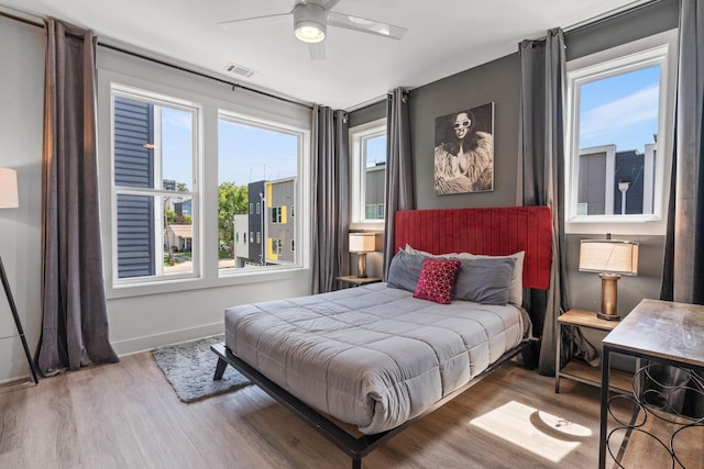 bedroom featuring visible vents, baseboards, ceiling fan, and wood finished floors