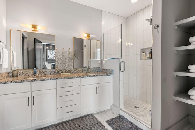 bathroom with marble finish floor, a sink, double vanity, and a shower stall
